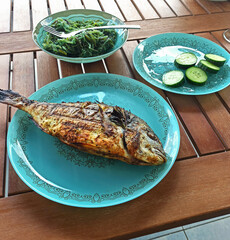 roasted dorado or sea bream fish with lemon and orange slices, spices, fresh parsley and spinach on...