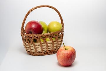 Red and green apples in a wicker basket isolated on white background. Close up.
