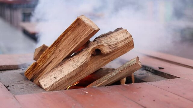 Burning firewood on a special table at a fair. A metal brazier with a hole in the middle for burning firewood, an open fire. A close-up of a fire. Lighting a fire, lots of smoke
