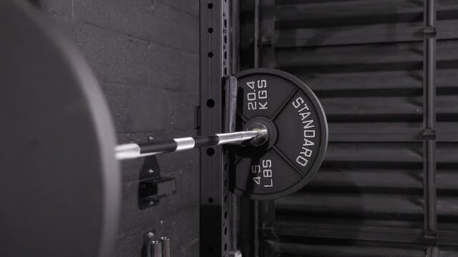 a barbell with a 45 pound plate is seen loaded on a squat rack