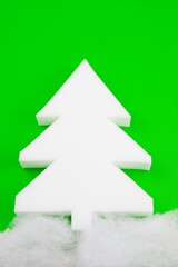 A white styrofoam Christmas tree stands out on a beautiful green background