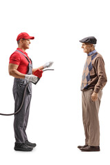 Petrol station worker holding a refuel gun and talking to an elderly man