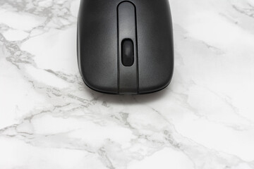 Black computer mouse is sitting on a white marble countertop