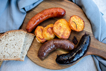 Close-up of homemade blood sausage, pork sausage and chorizo on wooden board with potatoes....