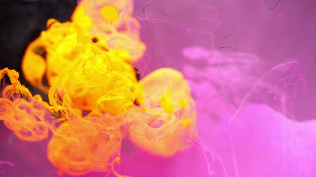 Abstract background. Yellow ink breaks up in water with a pink tint creating deep structures.