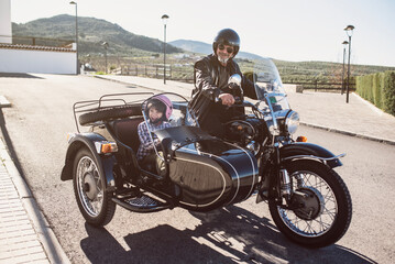 Little boy with his grandfather on sidecar bike.