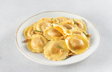 Ravioli pasta filled with pumpkin, nuts and fresh herbs on white background. Top view. Copy space.