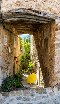 Narrow stone alleyway with yellow umbrella in Valldemosa