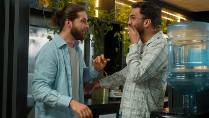 Diverse happy friends coworkers colleagues business men Arabian Indian Caucasian guys businessmen talking in bar office break sharing gossip secret on ear gossiping amazing news laugh male friendship