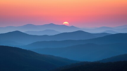 Fototapeta premium The sun sets behind the mountains, casting a hazy sky in both the foreground and background