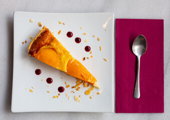 Piece of caramel peach flan sprinkled with almond flakes served in coffeehouse