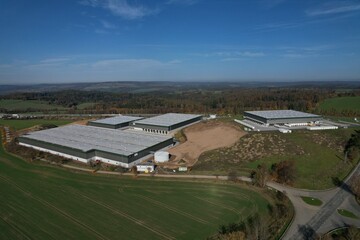 Obraz premium Solar panels installed on a roof of a large industrial building or a warehouse. Modern Industrial buildings in the background. Horizontal photo.Aerial panorama landscape of solar powerplant on roof 