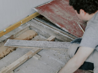 A young man pulls boards out of the floor.