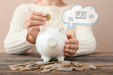 Woman putting coin into piggy bank on table, closeup