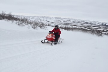 Caucasian male riding red snowmobile on snowy landscape