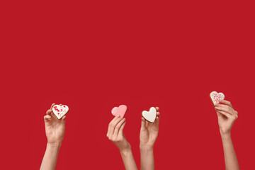 Women with heart-shaped cookies on red background. Valentine's Day celebration