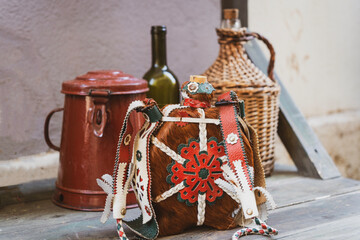 Water bottle decorated with Hungarian folk motifs with old rustic dishes in the background