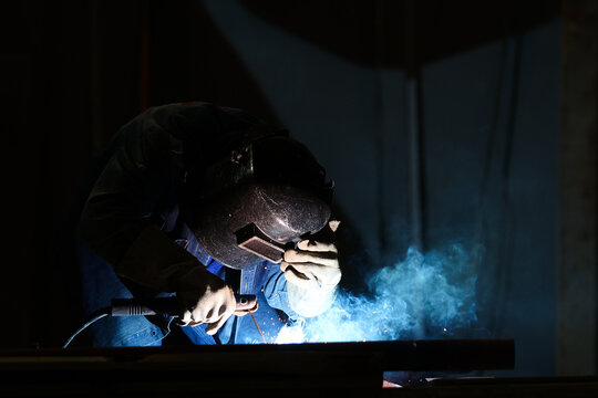 blacksmith welding metal structure wearing helmet