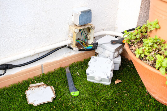 Damaged outdoor electrical cable box replaced with a new unit in backyard garden area