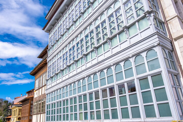 A large white building with numerous windows on the side, typical of Asturian houses in Llanes,...
