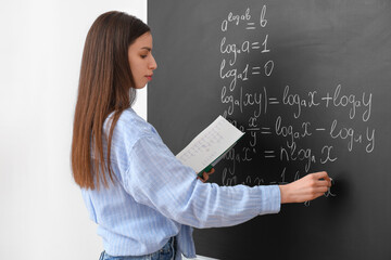 Young female math teacher near chalkboard in classroom