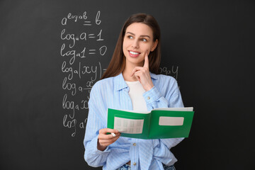 Thoughtful female math teacher near chalkboard in classroom