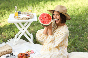 Beautiful young woman with watermelon at picnic in park