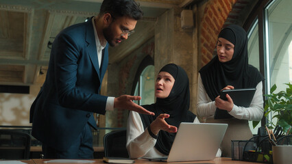 Arabian male female businessman businesswoman come to employee working laptop two mentors teach...
