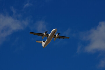 A small turbo propeller aircraft photographed from the ground