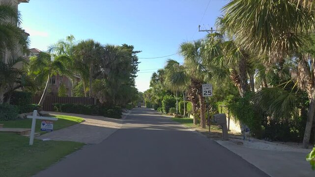 Driving on Florida scenic road. Car point of view of Casey Key coastal neighborhood with tropical nature and southern architecture