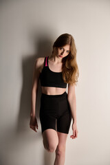 Fototapeta premium Attractive young adult in sportswear posing on white background. Sexy and sensual brunette woman with perfect body posing in studio isolated over white background