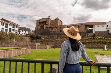 Young Latin tourist observing the Qoricancha and the Santo Domingo convent, a temple built in the Inca style.