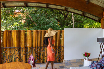 an African American woman with long sister locks wearing an orange dress and a hat dancing at a resort in Liberia Guanacaste Costa Rica