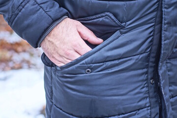 part of black winter jacket with hand in pocket on one man on winter street