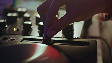 Hand adjusting slider DJ equipment in nightclub closeup. Unknown disc jockey