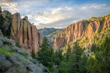 Views of the National Park's majestic canyons, with the sun setting behind the jagged cliffs, casting golden light across the landscape,