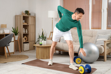 Sporty young man suffering from back pain at home