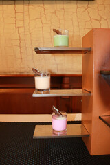 A creative display of green, white, and pink puddings served in glasses, garnished with biscuits,...