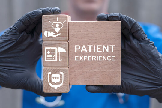 Doctor holding wooden blocks sees inscription: PATIENT EXPERIENCE. Health care concept of patient experience.