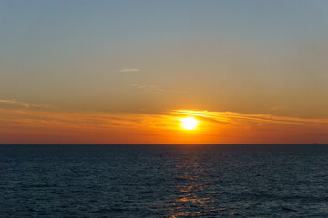 Naklejka premium Calm sea with waves and sunset at moody colorful yellow and orange sky
