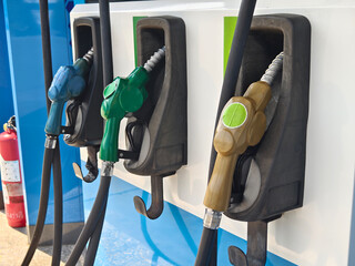 Fuel dispenser nozzles for various types of fuel, arranged at a gas station.
