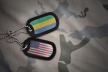 army blank, dog tag with national flag of gabon and united states of america on the khaki texture...