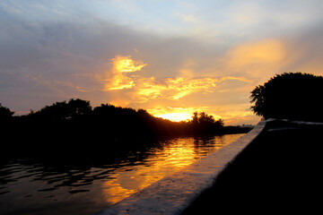 - Panoramic view of the beautiful sunset over the waters of the Caño de la Ahuyama in Barranquilla, Colombia. Water reflection. Vintage film aesthetic.