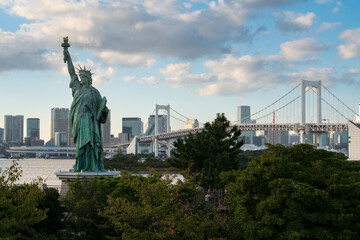 Fototapeta premium Statue of Liberty on Odaiba Island and Rainbow Bridge Suspension Bridge over North Tokyo Bay on a sunny autumn day, Tokyo, Japan