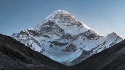 Mt. Kailash Tibet Sacred Peak. The sacred peak of Mount Kailash under clear skies, with the sunlight casting a soft glow on the snow-covered summit and the surrounding barren landscape