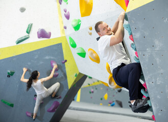 Man climbs steep artificial wall in sports complex and trains endurance and muscle strength. Active...