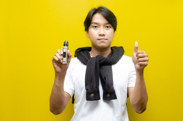 Young Asian Man Holding E-Cigarette Amidst Thick Clouds of Vapor