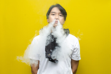 Young Asian Man Exhaling Thick Smoke or Vapor from a Cigarette or E-Cigarette