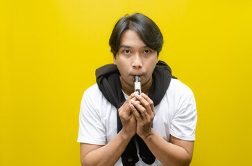 Young Asian Man Holding E-Cigarette Amidst Thick Clouds of Vapor