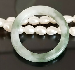 Elegant Jade Ring and Pearl Necklace on a Black Mirror Display